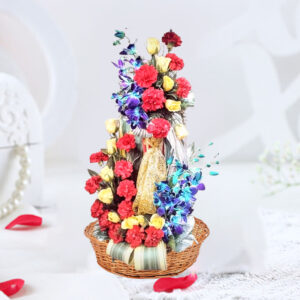 An enchanting floral arrangement featuring 18 red Carnations, 14 yellow Roses, and 6 blue Orchids, presented in a cane basket with golden net embellishment, accompanied by China Palm and Dressina leaves.