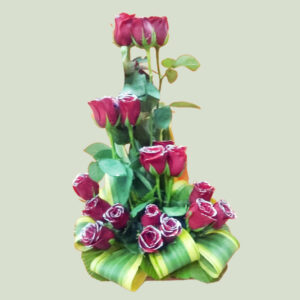 18 red roses elegantly arranged in a classic cane basket, accentuated by the vibrant beauty of Dressina Green fillers.