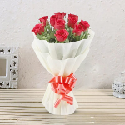 A charming bouquet featuring 10 Red Roses wrapped in cream non-woven packing paper, adorned with a red ribbon bow and golden filler.