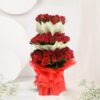 A stunning bouquet of 100 red Roses, adorned with red and white non-woven packing sheets, tied with a red net ribbon bow, and accented with lush green fillers