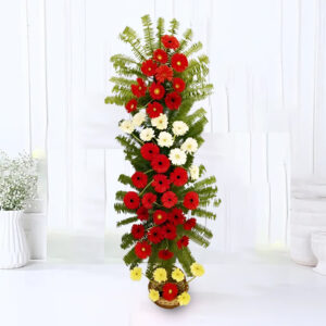 A stunning floral arrangement featuring 30 Red Gerberas, 10 White Gerberas, and 6 Yellow Gerberas, complemented by Fern leaf filler, elegantly presented on a 3-tier cane stand.